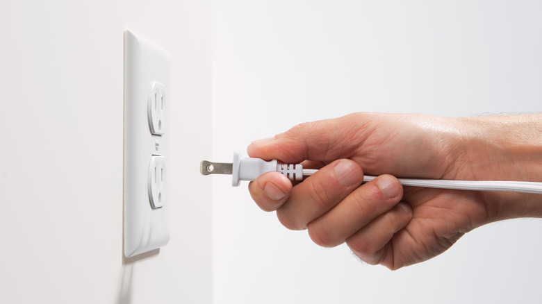 Person plugging cord into outlet