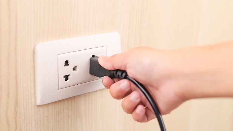 Hand plugging cord into outlet