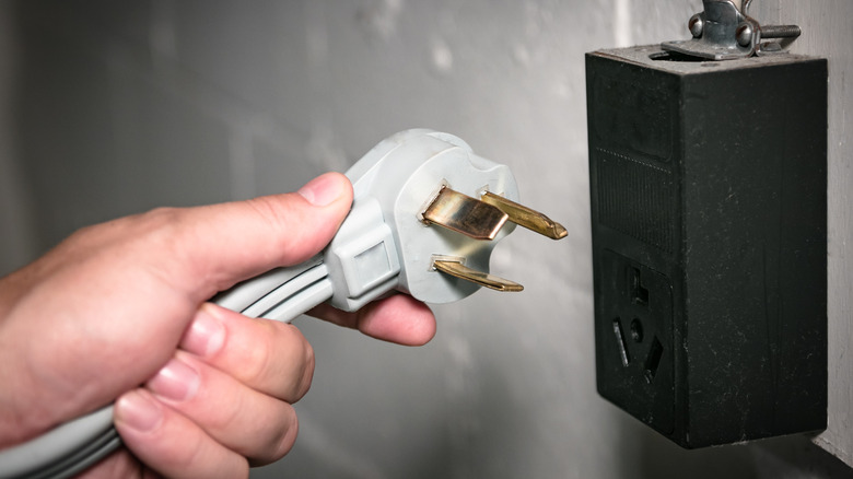 240-volt electrical outlet with a hand a plug