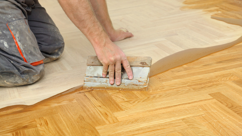 person varnishing hardwood floors 