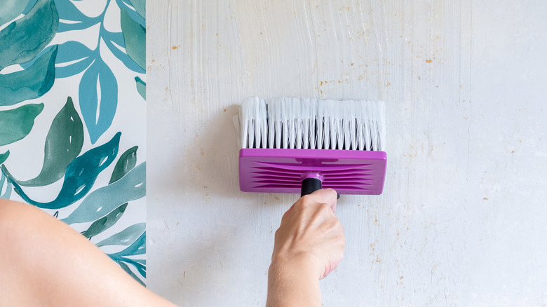 Person applying wallpaper paste with pink brush