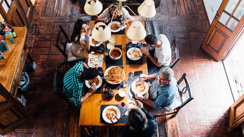 Family eating in dining room with wooden table, floors, and door