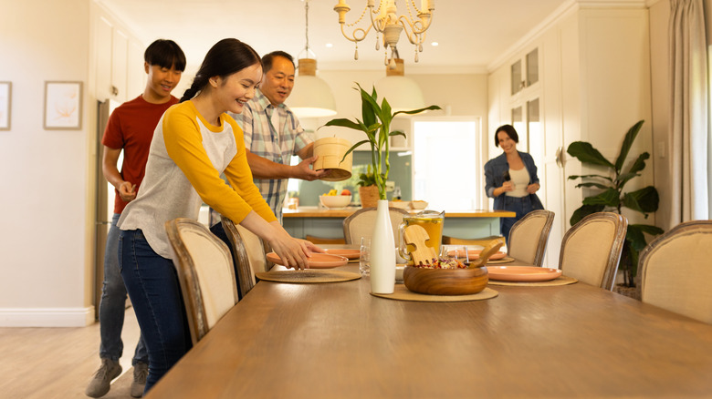 family setting the dining room table for dinner