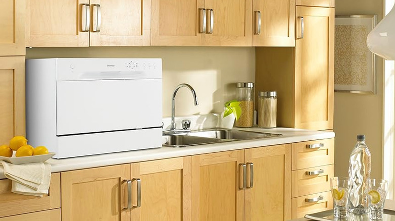 A white countertop dishwasher next to sink