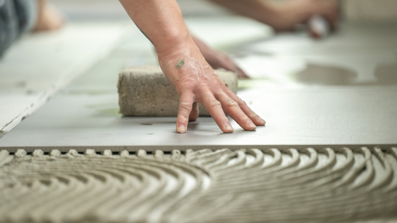 Person installing large tile with no space for grout