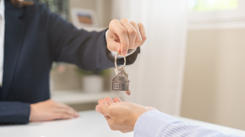 Hands exchanging keys with a model home attached