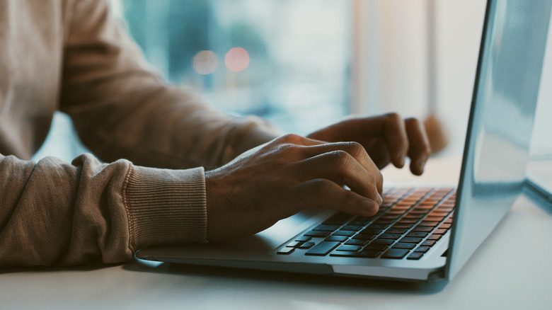 Hands typing on a laptop