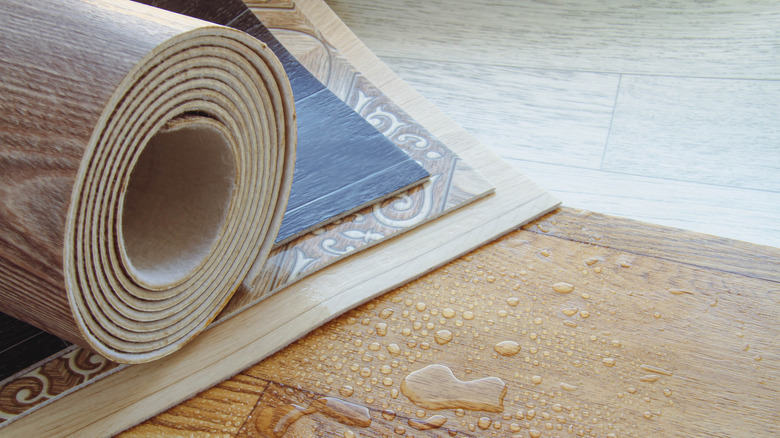 Rolled up sheet of vinyl flooring next to wet vinyl