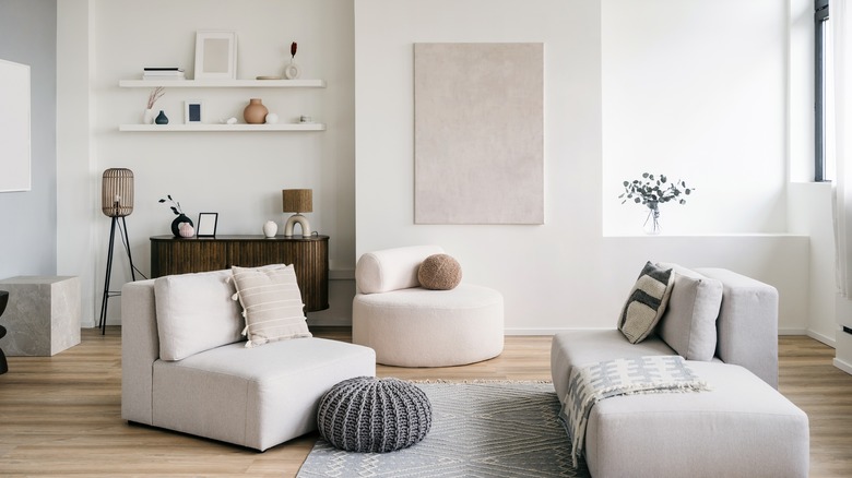 Living room with two white couches, wall art, hanging shelves and a plant