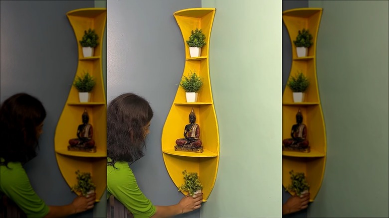 woman putting plant on corner shelf