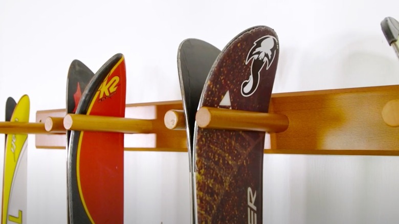 Skis are hung from their tips on a wood rack