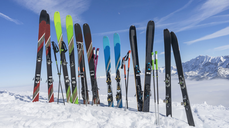 A line of skis and poles are stuck into the snow