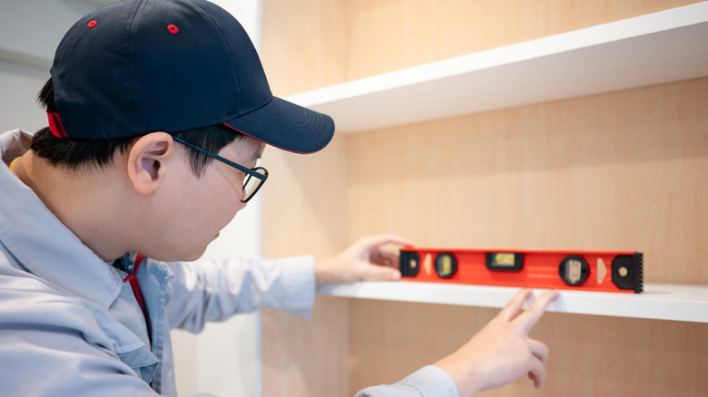 Person using a level on a custom-built garage cabinet shelf