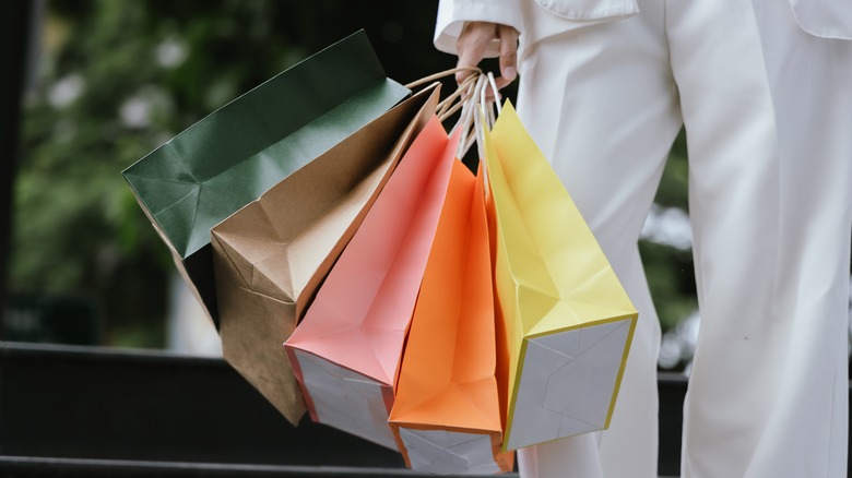 A person holds multicolor paper shopping bags