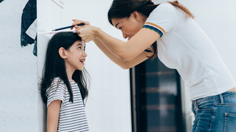 Mother measuring daughter's height