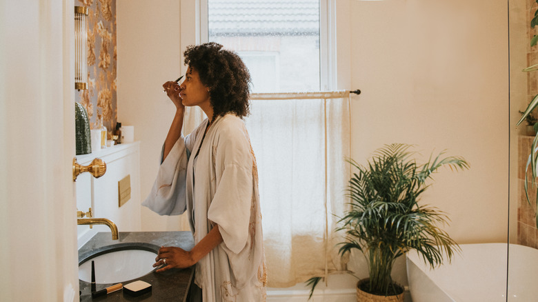 A woman gets ready for the day using her mirror cabinet