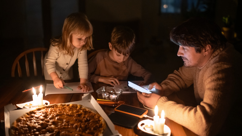 A family sits around a table during a power outage with candles lit.