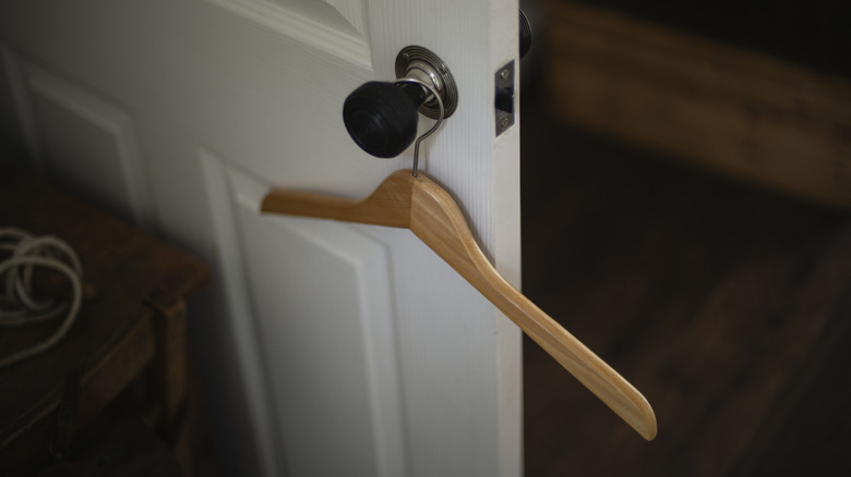 A coat hanger hangs over the handle of a entryway closet door.