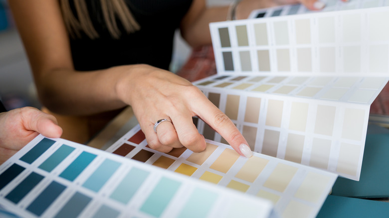 A woman choosing paint colors for a DIY closet door decoration project.