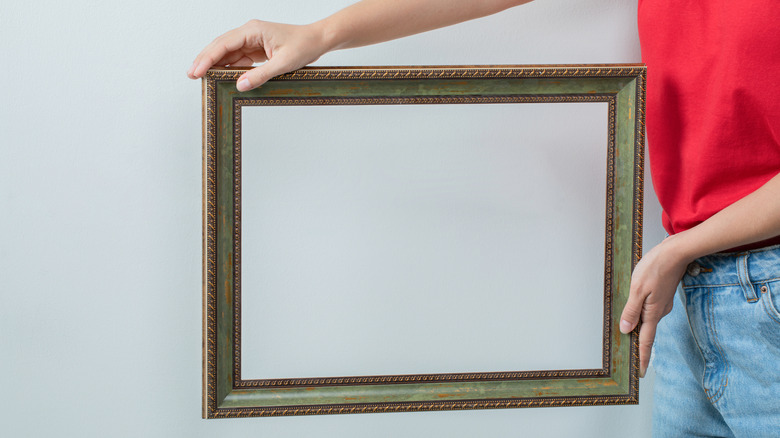 Girl holding an empty picture frame to mount on the wall