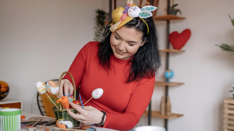 Woman making Easter basket with egg decorations