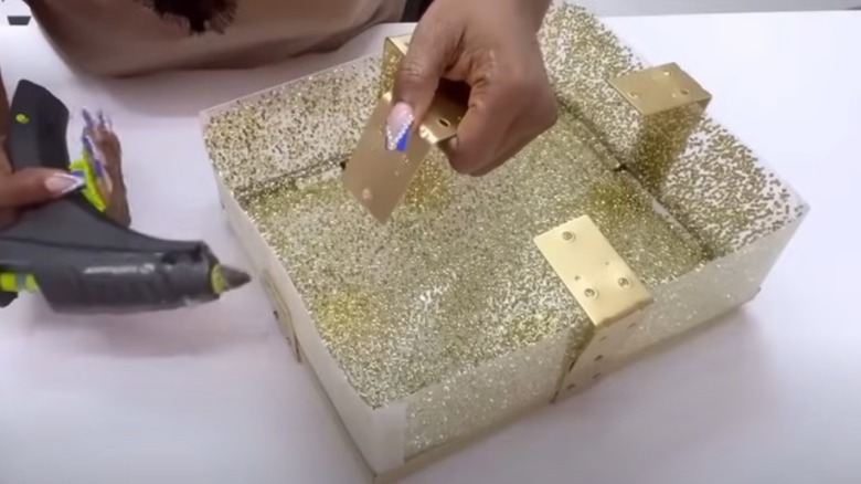 Person drilling screw holes in glitter frame