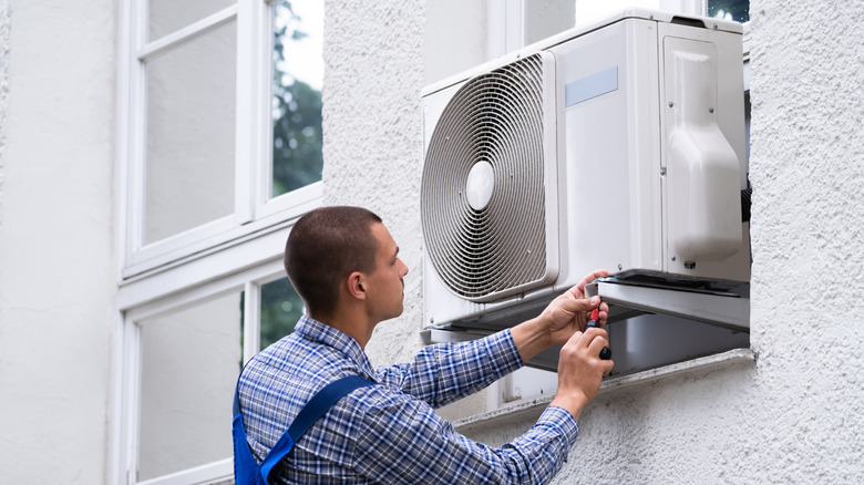 man working near window AC unit