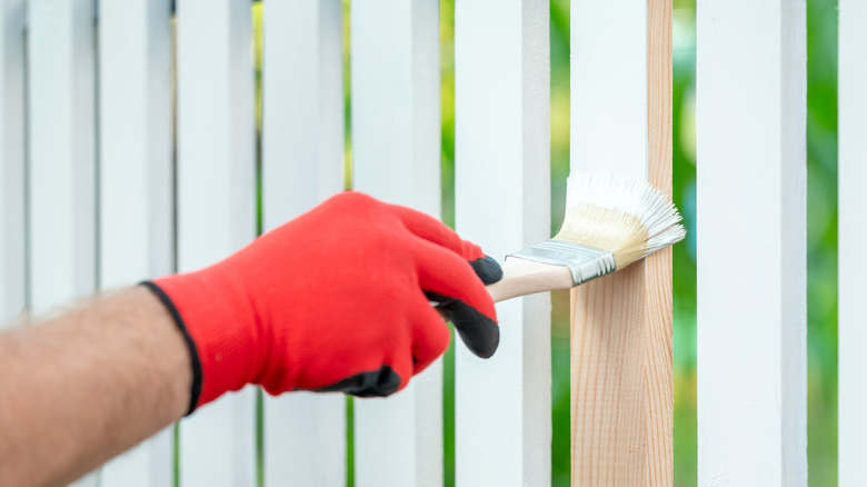 Person painting a wood fence panel