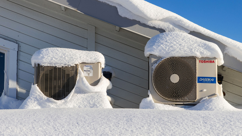 Outdoor heat pump units on a roof covered in snow in winter