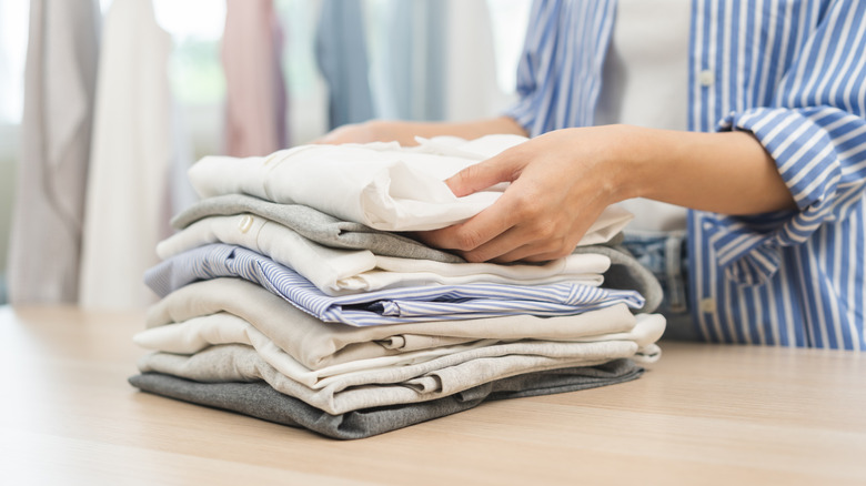 A person folding clothes and placing them on top of each other