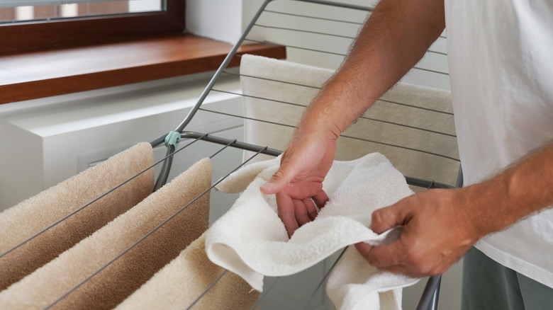 Person hanging towels on a heated airer to dry