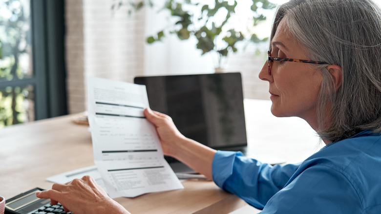 woman and paperwork by computer