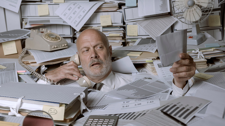 man falling under paperwork