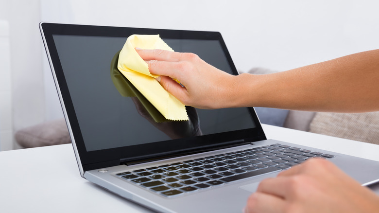 Person cleaning a computer screen