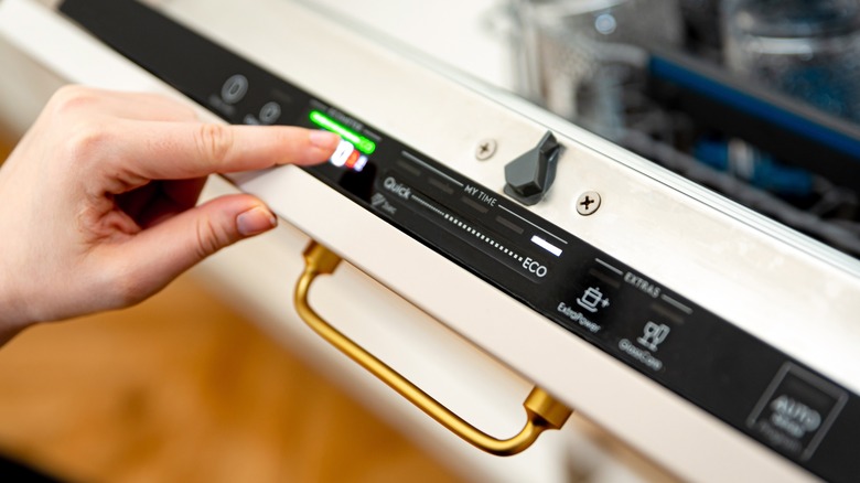 Person pressing button on dishwasher