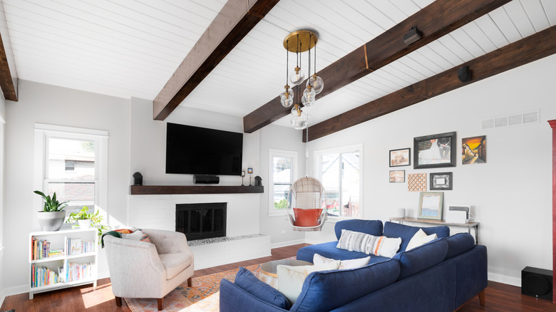 A living room with a white shiplap ceiling and dark wood beams