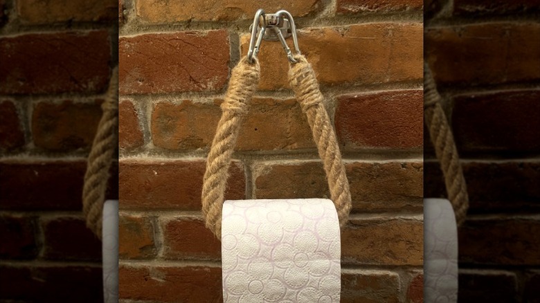 Toilet paper roll on rope toilet paper holder with carabiners on brick wall