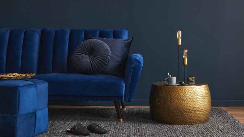 blue velvet couch next to hammered brass side table