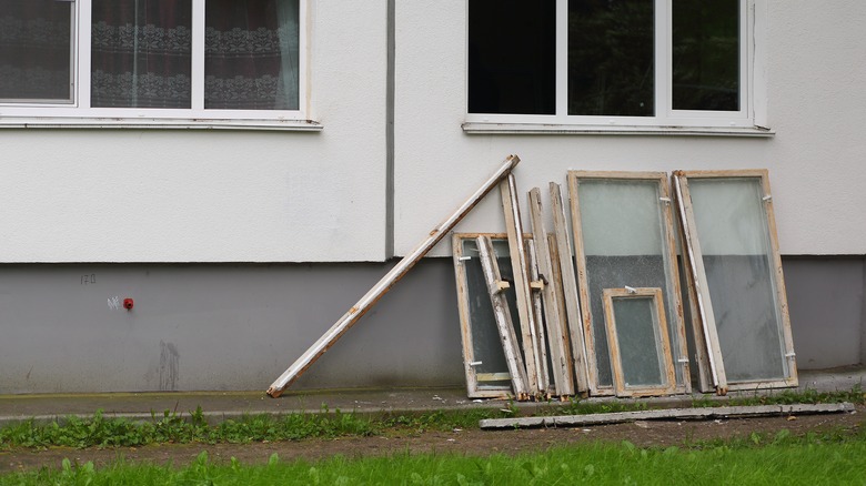 Stack of old wooden windows leaning against a building