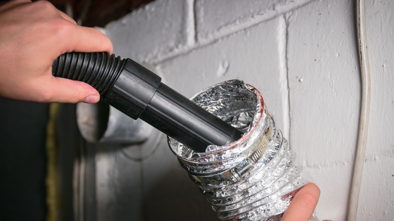 Person vacuuming a dryer hose