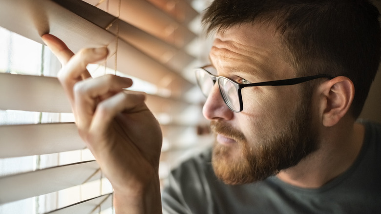 man looking through blinds