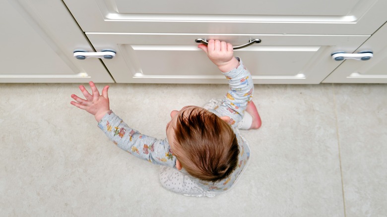 child pulling up on cabinets