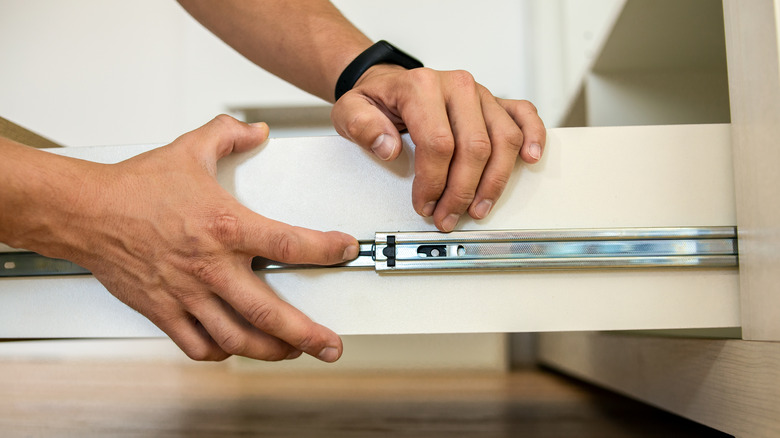 A person fits a cabinet drawer slide into place