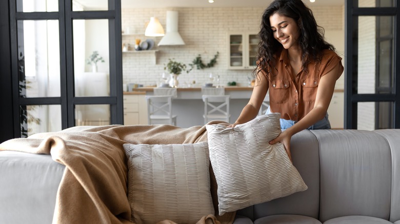 Person fluffing couch pillow