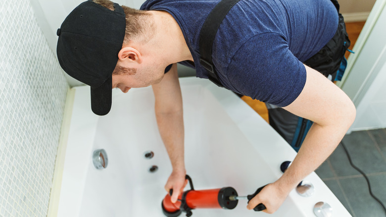 Professional plumber working on bathtub