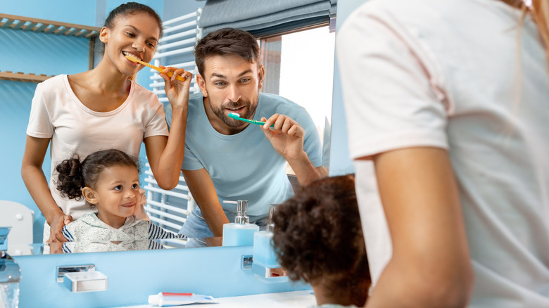 Family brushing teeth over sink