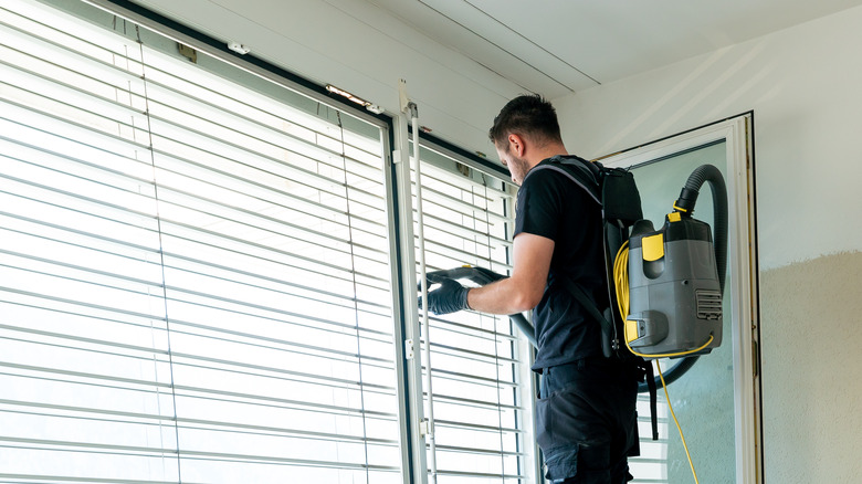 Man vacuumning blinds