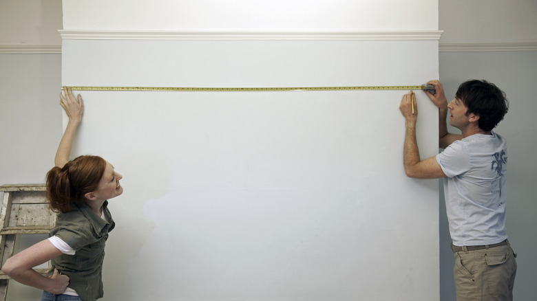 A couple measuring the length of a wall