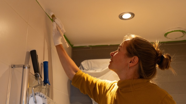 Woman painting the ceiling above a shower