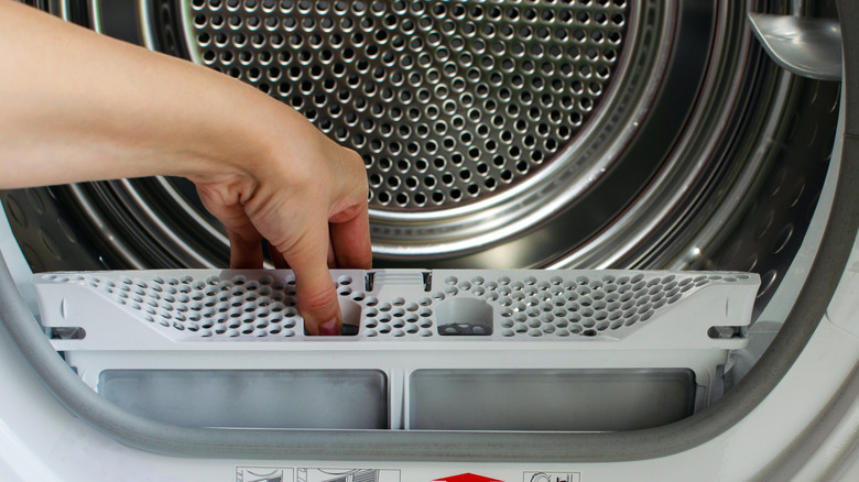 Person putting lint tray inside trap